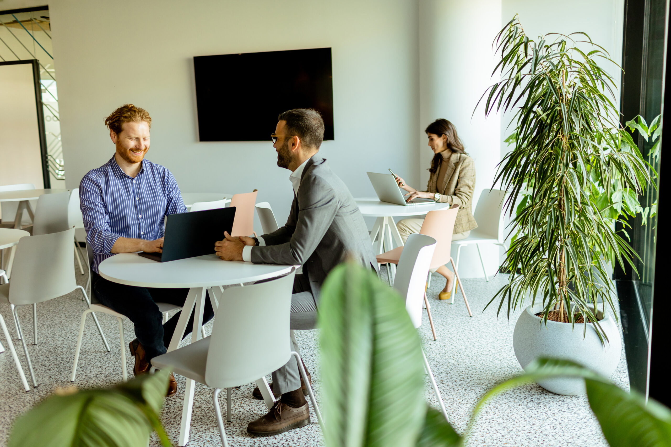 Two men engaged in deep discussion while working on a laptop at a modern table.